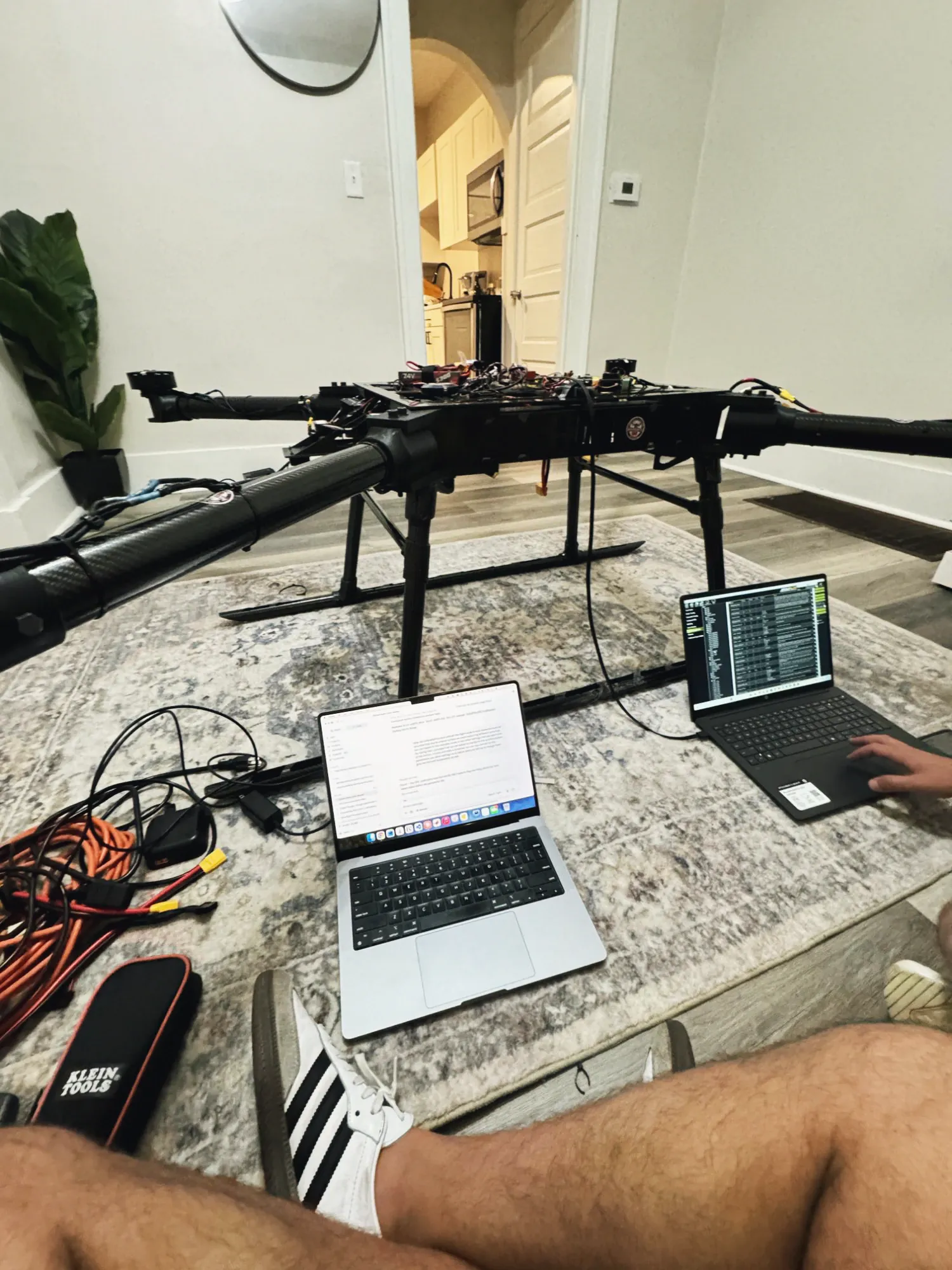 Two laptops on a rug beside the MW-V1, one showing a Mission Planner parameter list.